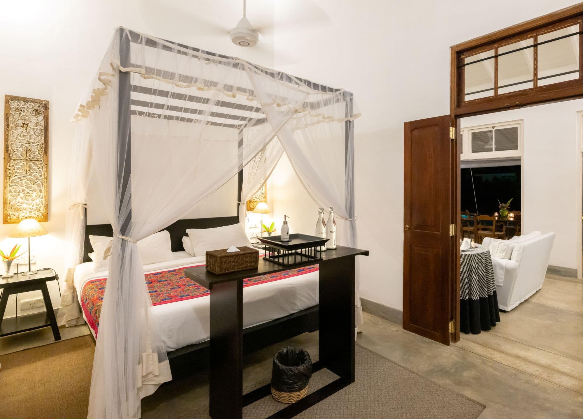 Bedroom with a canopy bed featuring a white mosquito net and dark wood furniture