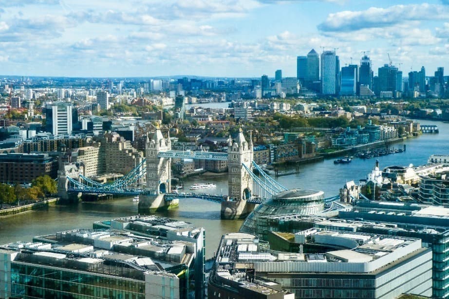 Aerial view of Tower Bridge crossing the River Thames with the city skyline in the background under a cloudy sky